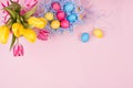 Gentle elegant soft pastel easter decoration - painted eggs, yellow tulips, cupcake on pink background, copy space, top view. Royalty Free Stock Photo