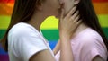 Gentle embrace of beautiful lesbians on rainbow flag background, love partners