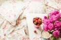 Gentle flowers are pink peonies, coffee with fluffy white milk foam and strawberries near the tender bed.