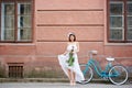 Gentle girl in light dress with peonies looked down