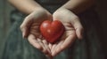 Gentle hands cradling a vibrant red heart, symbolizing love, health, and the spirit of giving and compassion