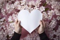 Gentle hands hold an ethereal, empty paper heart, set against a backdrop of vibrant flowers