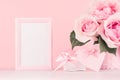 Gentle home decor for Valentines day - roses bouquet, gift box, blank frame, soft light pink heart with ribbon on white wood board Royalty Free Stock Photo