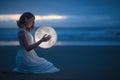 Gentle image of a girl, Astrology, Female magic. Beautiful attractive girl on a night beach with sand hugs the moon, art