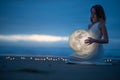 Gentle image of a girl, Astrology, Female magic. Beautiful attractive girl on a night beach with sand hugs the moon, art Royalty Free Stock Photo