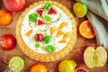 Gentle magnificent biscuit with vegetable vanilla cream decorated with fruit, a bud of a rose and young leaves on a wooden table