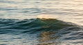 Gentle ocean waves roll gracefully under the warm glow of sunset light. The surface Royalty Free Stock Photo