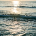 Gentle ocean waves under a setting sun create a serene seascape. The sun\'s reflection forms a Royalty Free Stock Photo