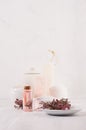 Gentle pink cosmetics oil, small flowers and white soap, cream, clay, towel on white wooden shelf, copy space, vertical. Royalty Free Stock Photo