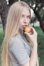 Gentle portrait of a beautiful cute girl with long blond hair with full lips and blue eyes with apple in hand, look at the camera Royalty Free Stock Photo