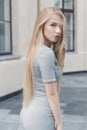Gentle portrait of a beautiful cute girl with long blond hair with full lips and blue eyes in a gray suit, look at the camera Royalty Free Stock Photo