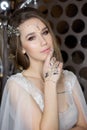 Gentle portrait of a beautiful cute happy bride with a beautiful hairdo festive bright make-up in a wedding dress with earrings an