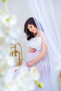 Gentle pregnancy. Beautiful pregnant in light white dress with orchids Royalty Free Stock Photo