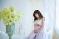 Gentle pregnancy. Beautiful pregnant in light white dress with orchids Royalty Free Stock Photo