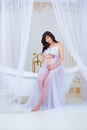 Gentle pregnancy. Beautiful pregnant in light white dress with orchids Royalty Free Stock Photo