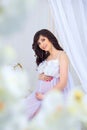 Gentle pregnancy. Beautiful pregnant in light white dress with orchids Royalty Free Stock Photo