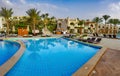 A gentle sunrise over the swimming pool with the some beach lounges Royalty Free Stock Photo