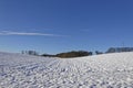 A gentle V shaped Valley with a snow covered ploughed field with all the furrows covered in snow.