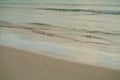 Gentle waves on the beach in the morning. Fading footprints in the sand in warm pastel colors. Royalty Free Stock Photo