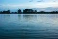 Gentle waves on the lake, trees on the horizon and clouds in the sky