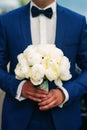 Wedding bouquet of white peonies in the hands of the groom