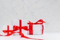 Gentle white gift boxes with red silk bow on wood table in white interior as festive anniversary background. Royalty Free Stock Photo