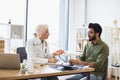 Gentleman describing symptoms of illness to senior female doctor. Royalty Free Stock Photo