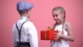 Gentleman kid presenting giftbox to his little girlfriend, birthday celebration