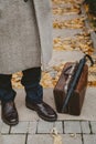 Man in coat stands in autumn park. Near carpetbag