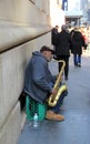 Gentleman playing musical instrument leaning against building,NYC,2015