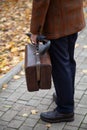 Man with carpetbag in jacket stands in alley of autumn park Royalty Free Stock Photo