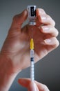 Genuine Pfizer-BioNTech COVID-19 Vaccine vial hold in hand with syringe needle next to it. Real vaccine photo. Selective focus.