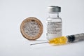 Genuine Pfizer BioNTech COVID-19 Vaccine vial, syringe and British one pound coin. Real vaccine photo.