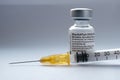 Genuine Pfizer BioNTech COVID-19 Vaccine vial and syringe next to it. Real vaccine photo. Selective focus.