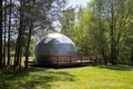 Geodesic dome glamping structure in forest clearing surrounded by lush greenery Royalty Free Stock Photo