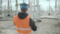 Geodesist in helmet and vest holds pole at electric station