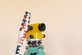 Geodesy level device on a tripod with ruler on the background a concrete pink wall. Royalty Free Stock Photo