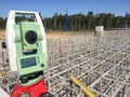 Geodetic total station on the top of the bridge pillar with scaffolding and trees in the background