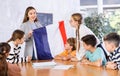 Geography lesson in school class - teacher talks about France, holding flag in his hands Royalty Free Stock Photo