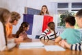 Geography lesson in school class - teacher talks about France, holding flag in his hands Royalty Free Stock Photo