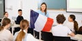 Geography lesson in school class - teacher talks about France, holding flag in his hands Royalty Free Stock Photo