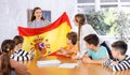 Geography lesson in school class - teacher talks about Spain, holding flag in his hands Royalty Free Stock Photo