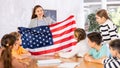 Geography lesson in school class - teacher talks about United States of America, holding flag in his hands Royalty Free Stock Photo