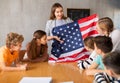 Geography lesson in school class - teacher talks about United States of America, holding flag in his hands Royalty Free Stock Photo