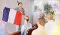 Geography lesson in university class - teacher talks about France, holding flag in his hands Royalty Free Stock Photo