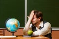 Geography teacher sits in front of a globe.