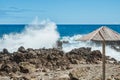 Powerful rock wave bursting in seascape with bamboo sunshade in Quatro Ribeiras, Terceira - Azores PORTUGAL