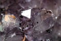 Gemstone Amethyst closeup as a part of cluster geode filled with rock Quartz crystals.