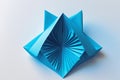 Geometric blue paper origami object with folded fan-like center on a white background studio shot Royalty Free Stock Photo