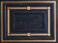 Geometric design fragment of modern luxury black wooden entrance door with carved panel and golden patina frames with classical or